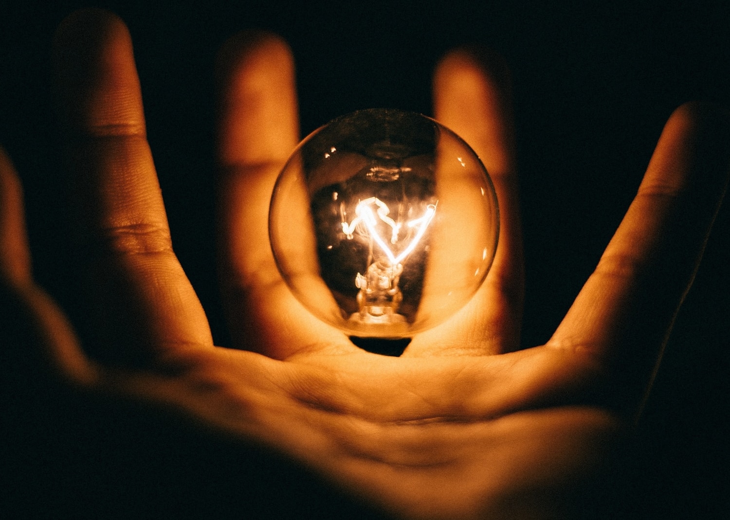 Hand holding a glowing lightbulb